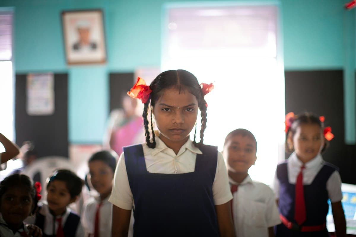 Girls and boys in school uniform standing in their classroom