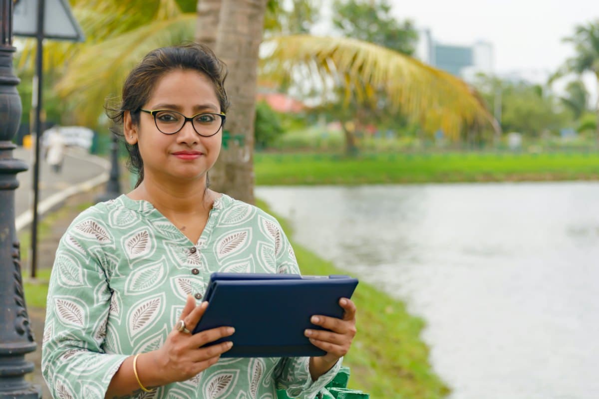 A smiling teacher holding a tablet outdoors